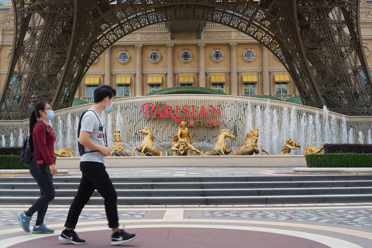 Människor går förbi en kopia av Eiffeltornet utanför det parisiska Macao den 10 april 2020. (Inuti A ...